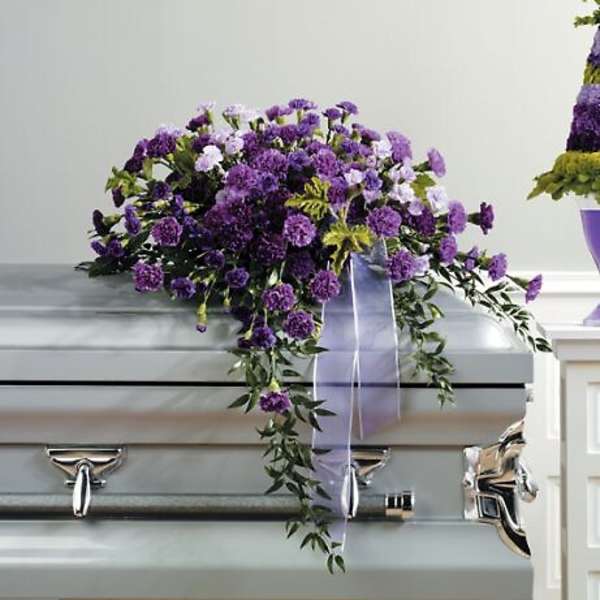 Purple floral casket spray with trailing ribbon