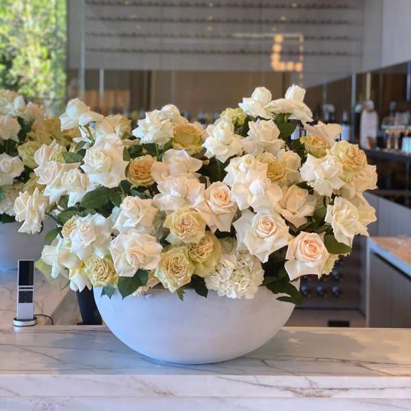 Large white rose arrangement in a round white bowl
