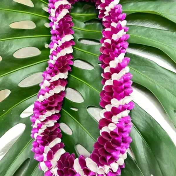 Purple and white flower lei on large tropical leaves