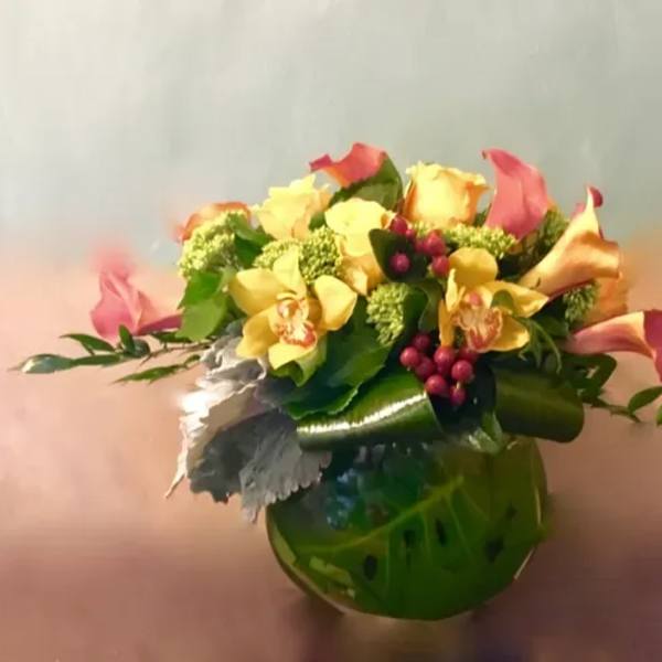 Bouquet of yellow roses and pink calla lilies in a green vase