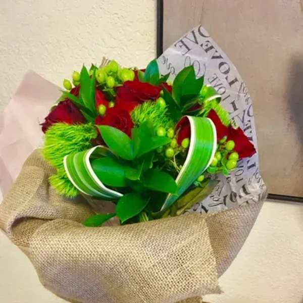 Bouquet of red roses wrapped in burlap with green ribbon