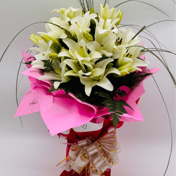 Tall arrangement of white lilies wrapped in pink paper with a large beige bow