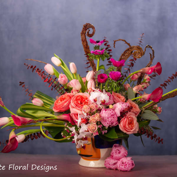 Pink and coral floral arrangement in a decorative ceramic vase