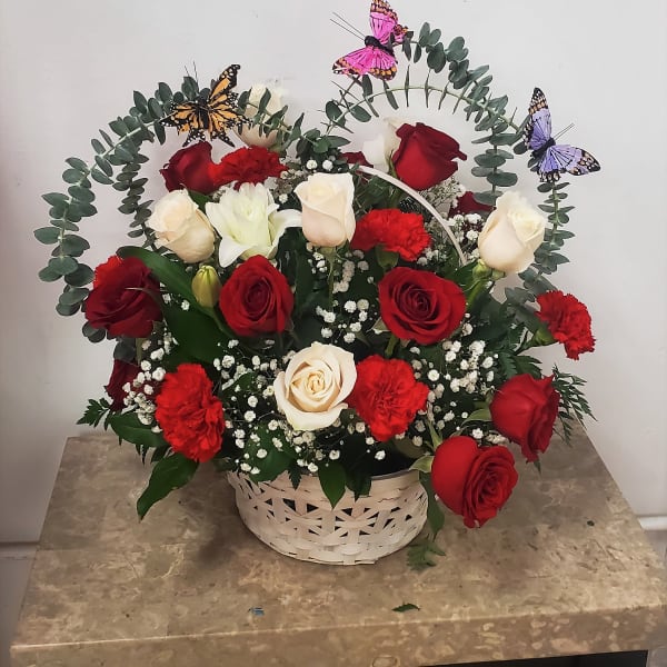 Basket arrangement of red and white roses with butterflies and eucalyptus