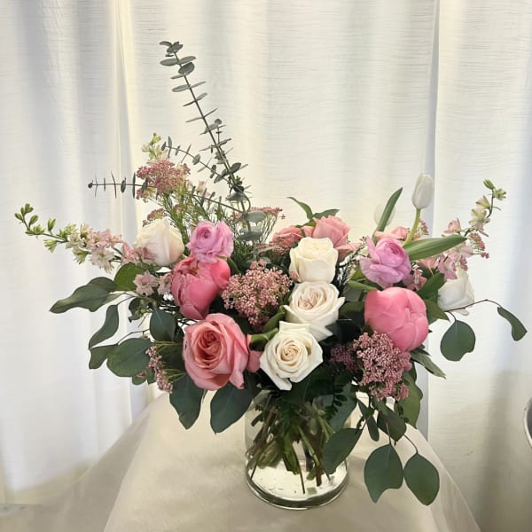 Pink and white roses arranged in a clear glass vase