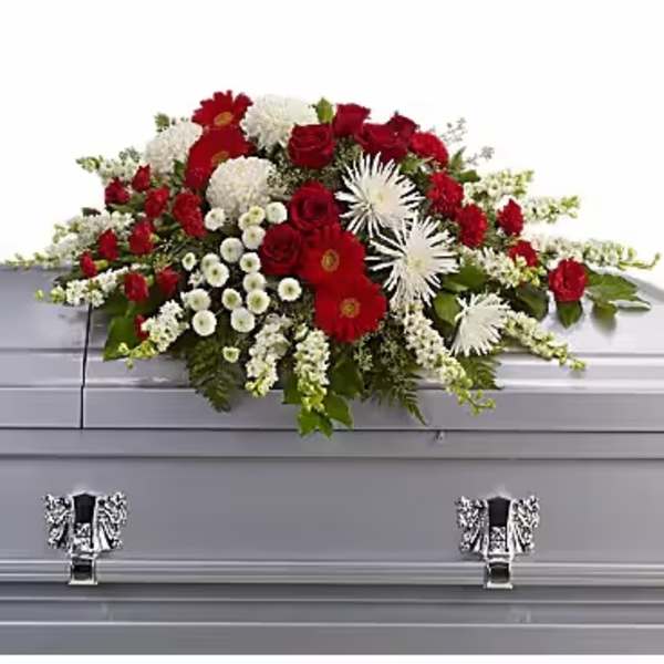 Red and white floral casket spray on a gray casket