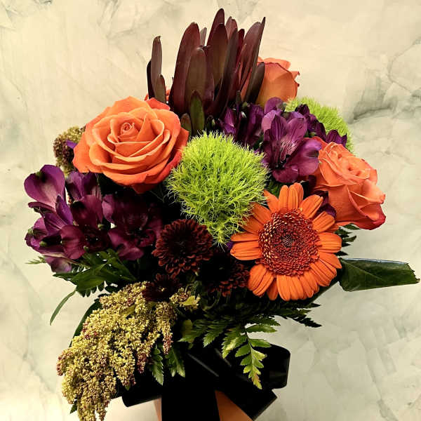Bouquet of orange roses and purple flowers with a black ribbon
