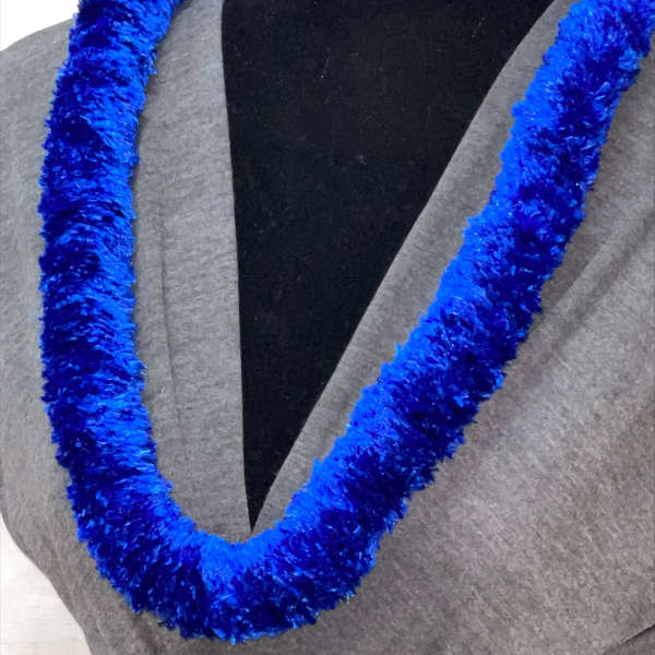 Bright blue fluffy lei necklace displayed on a dress form