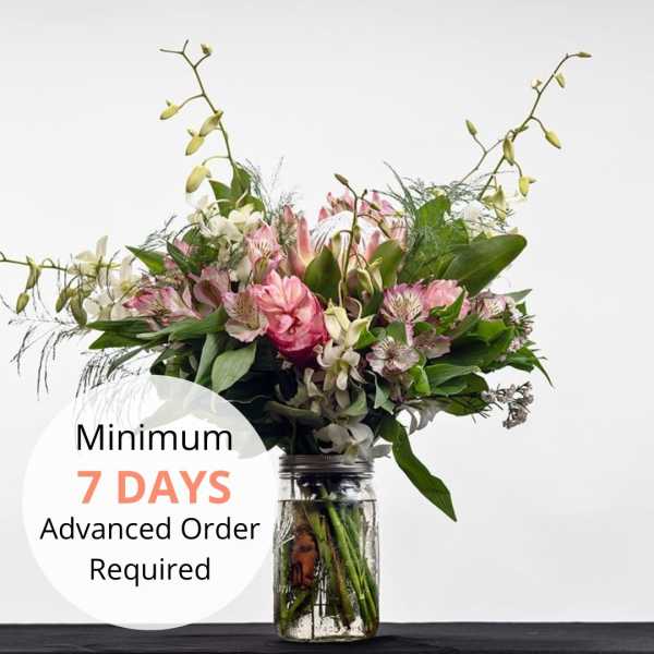 Pink and white mixed bouquet with orchids in a clear glass jar vase