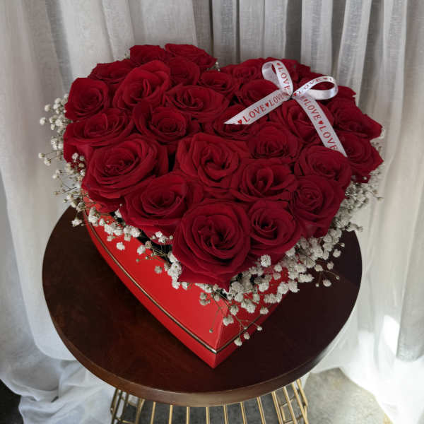 Heart-shaped box filled with red roses and baby's breath