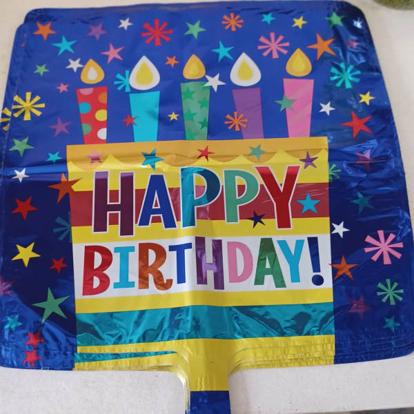 Square foil birthday balloon with colorful candles and Happy Birthday text on blue background