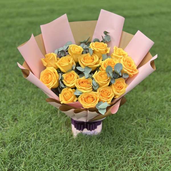 Bouquet of yellow roses wrapped in pink paper
