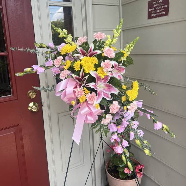 Standing floral spray with pink, yellow, and white flowers on an easel