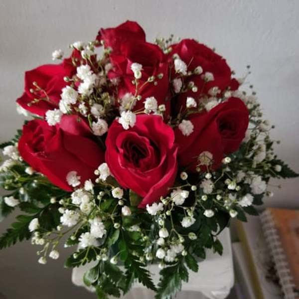Red roses with white baby's breath in a white vase