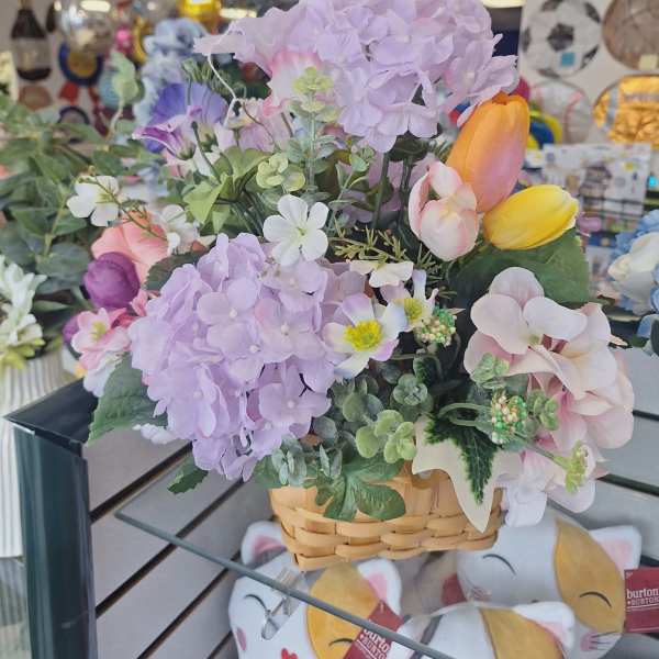 Basket of pastel artificial flowers with hydrangeas and tulips