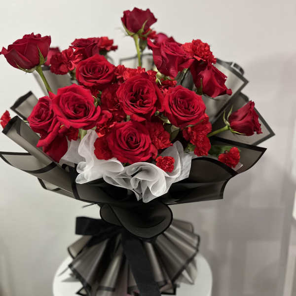 Bouquet of red roses and carnations wrapped in black and white paper