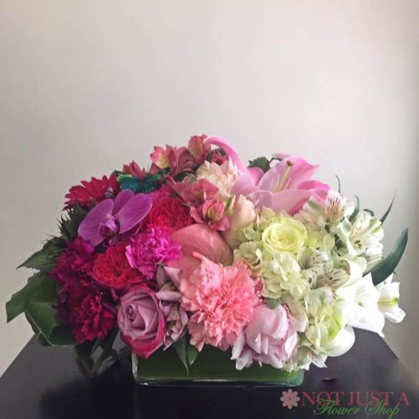 Pink and white mixed flower arrangement in a low rectangular vase