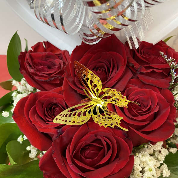 Red roses with a gold butterfly decoration in a gift box