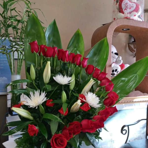 Red roses and white lilies in a large arrangement with green leaves