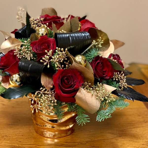 Red roses arranged with gold accents in a gold vase