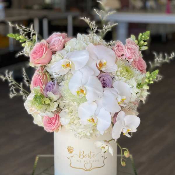 Pink and white floral arrangement in a white hat box