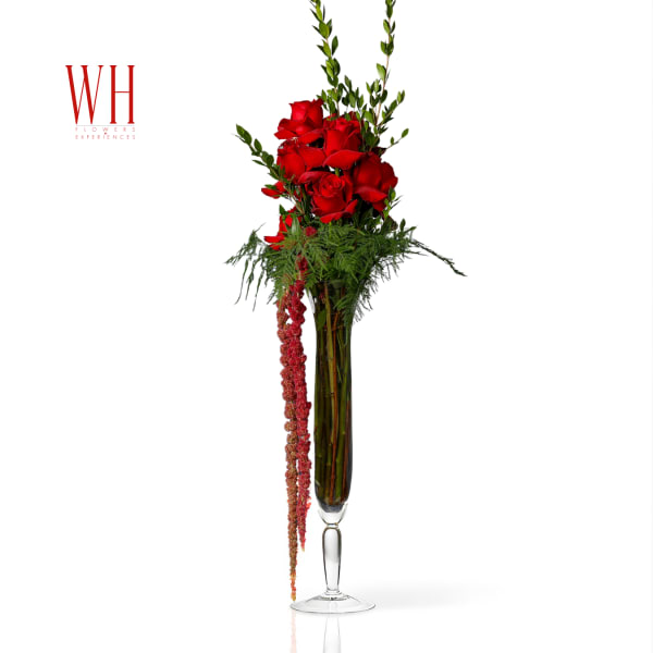 Tall red rose arrangement in a clear glass vase with trailing red flowers