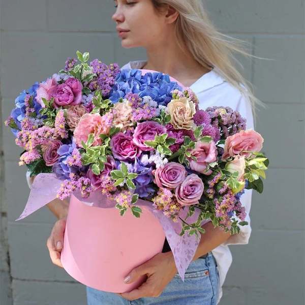 Large mixed bouquet in a pink hat box with pink, purple, and blue flowers