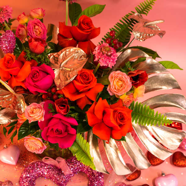 Bright bouquet of roses with metallic leaves and glitter heart decorations