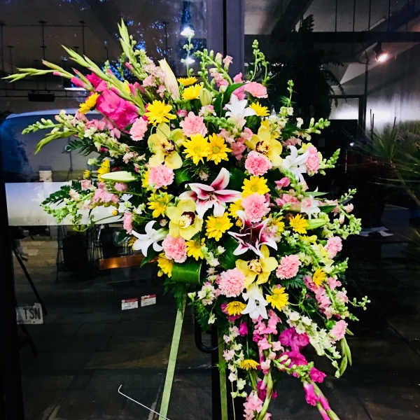 Large standing floral spray with pink, yellow, and white blooms