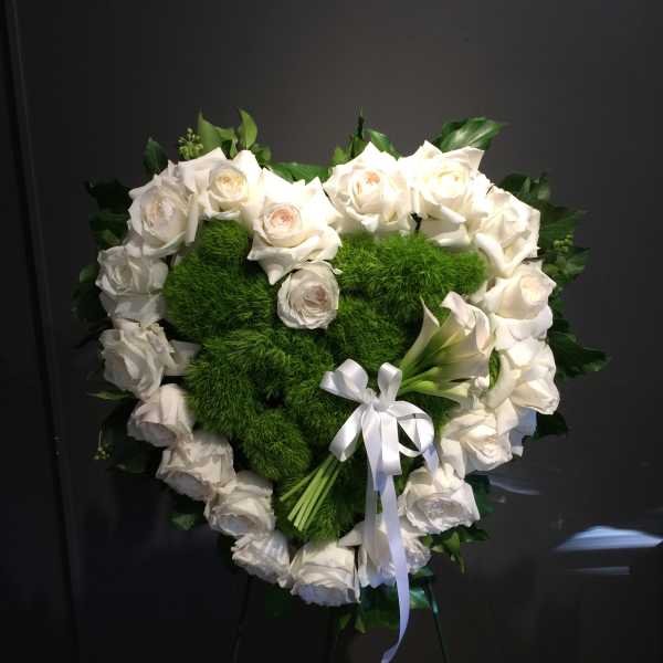 Heart-shaped white rose wreath with green center and white ribbon