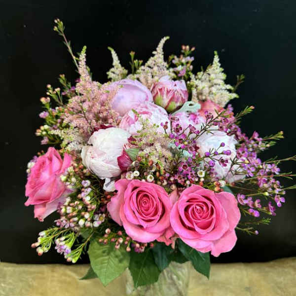 Pink and white bouquet of roses and peonies in a glass vase