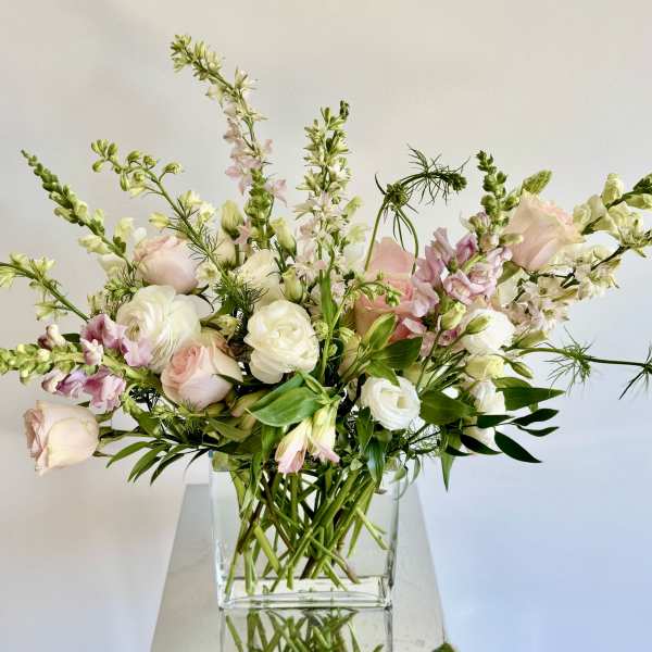 Loose bouquet of pale pink and white flowers in a clear glass vase