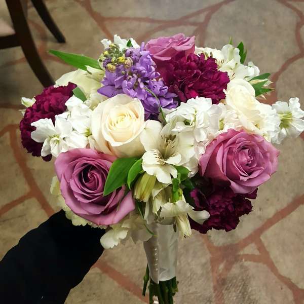 Handheld bouquet of pink, white, purple, and burgundy flowers