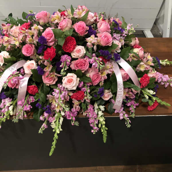 Large pink and purple floral casket spray with ribbon streamers