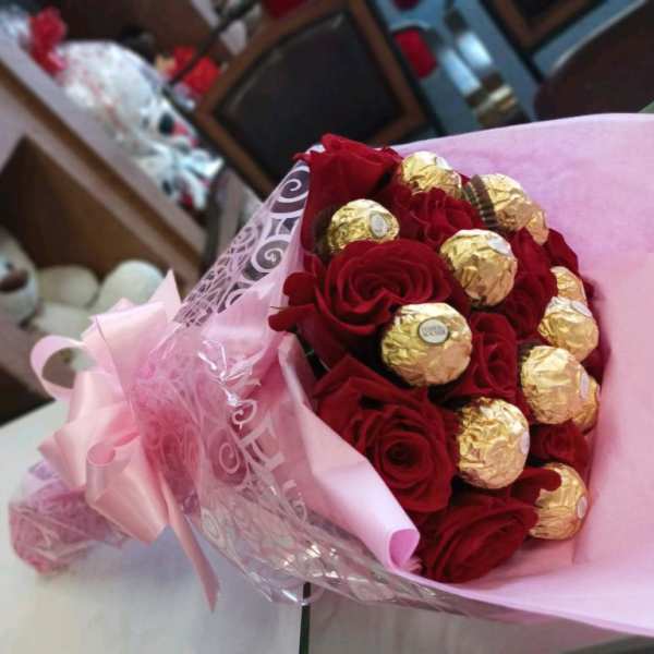 Bouquet of red roses with gold-wrapped chocolates in pink wrapping