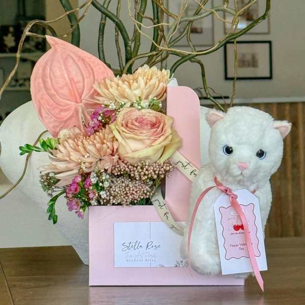 Pink floral gift box with a white plush cat and pastel bouquet