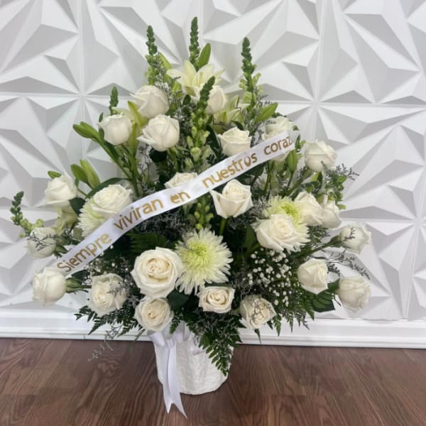 White rose and lily arrangement in a white basket with a ribbon