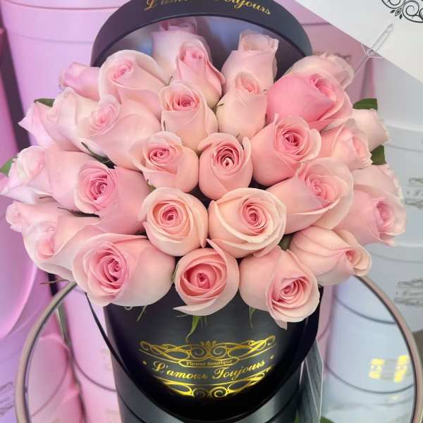 Pink roses arranged in a black round hat box