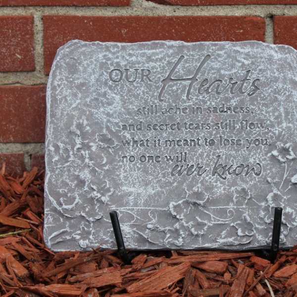 Gray memorial stone with an engraved heart quote on a brick wall