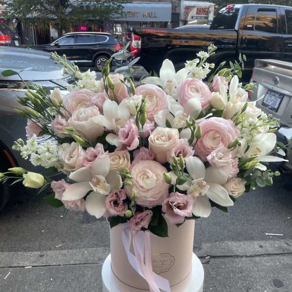Large blush and white floral arrangement in a round box with ribbon