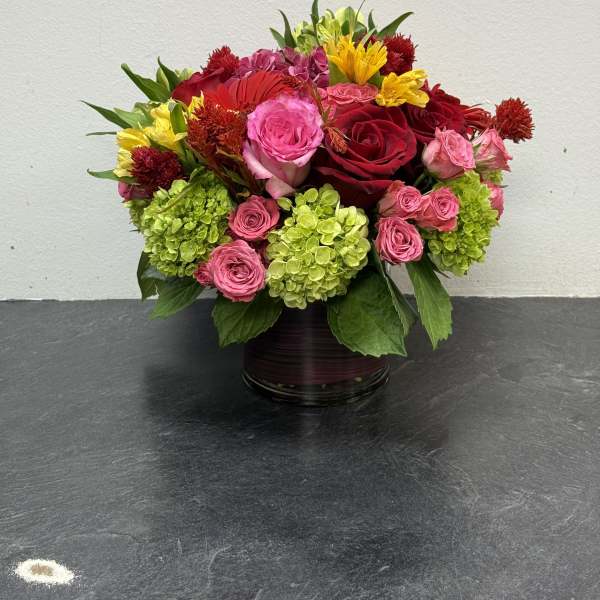 Mixed bouquet of pink and red roses with green hydrangeas in a glass vase