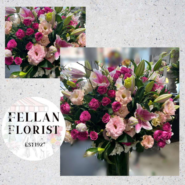 Large arrangement of pink roses, lilies, and peach lisianthus in a clear glass vase