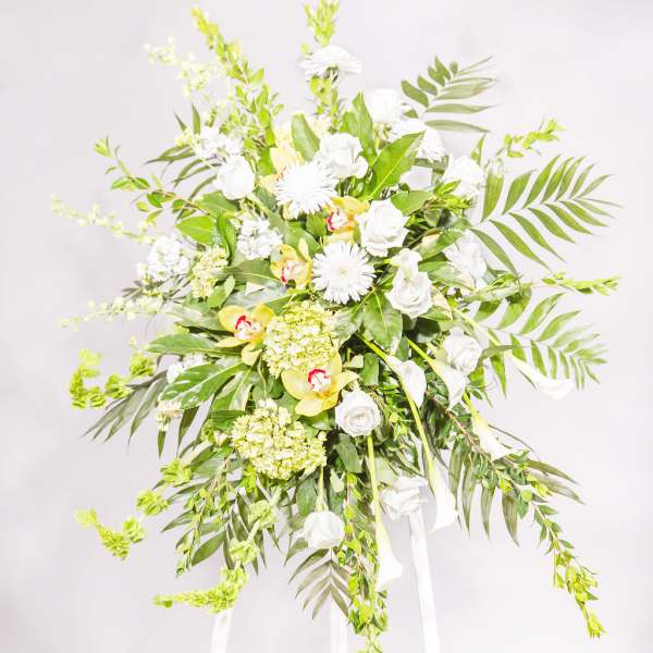 Tall white floral standing spray on a white easel
