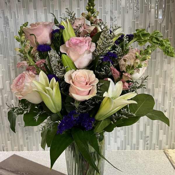 Pink roses and white lilies arranged in a clear glass vase