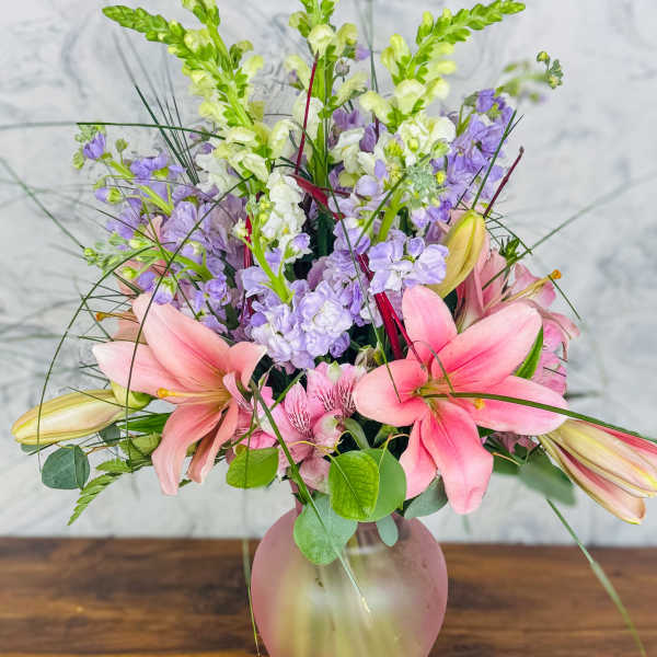 Pink lilies and lavender flowers in a frosted pink vase
