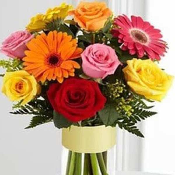 Mixed bouquet of roses and gerbera daisies in a clear glass vase