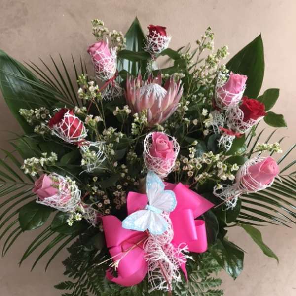 Bouquet of pink and red roses with a pink ribbon and butterfly decoration