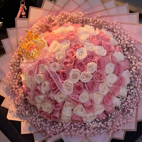 Large bouquet of pink and white roses with a pink ribbon and decorative wrap