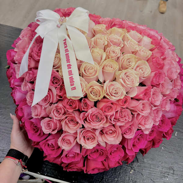 Large round bouquet of pink and blush roses with a white ribbon bow