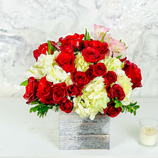 Red roses and white hydrangeas in a square wooden vase with pink lilies